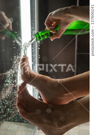 Foot fetish. A woman pours beer from a bottle onto her toes. Foot fetish. A woman pours beer from a bottle onto her toes. 137600241