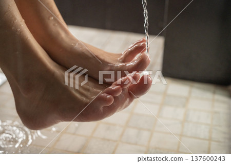 Foot fetish. A woman pours beer from a bottle onto her toes. Foot fetish. A woman pours beer from a bottle onto her toes. 137600243