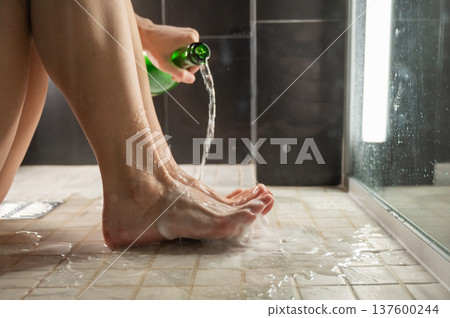 Foot fetish. A woman pours beer from a bottle onto her toes. Foot fetish. A woman pours beer from a bottle onto her toes. 137600244