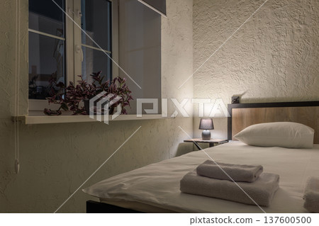 Cozy Budget Hotel Room Detail with Bedside Lamp and Bed 137600500