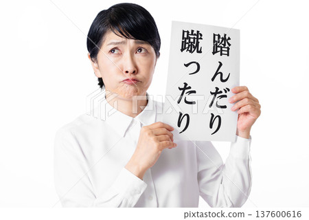 A senior woman wearing a white shirt holding a piece of paper with the words "kicked" written on it and pointing out A senior woman wearing a white shirt holding a piece of paper with the words "kicked" written on it and pointing out 137600616