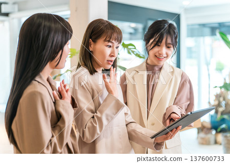 Businesswomen having a meeting while looking at a tablet Businesswomen having a meeting while looking at a tablet 137600733