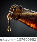 Closeup of soda bottle pouring amber stout beer slowly coming out of the opening of the bottle on dark background 137600962