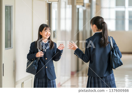 Female students, elementary school students, junior high school students, and high school students in uniform walking down a school corridor 137600986