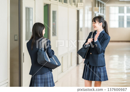 Female students, elementary school students, junior high school students, and high school students in uniform walking down a school corridor 137600987