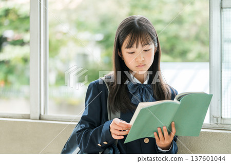 小學、國中和高中女生在學校走廊拿著書 小學、國中和高中女生在學校走廊拿著書 137601044
