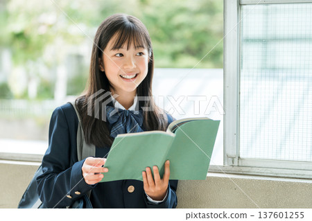 Elementary school, junior high school, and high school girls holding books in school corridors 137601255