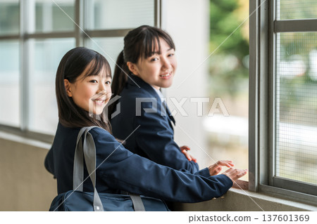 一群穿著校服的國中女生在學校走廊上聊天。 一群穿著校服的國中女生在學校走廊上聊天。 137601369
