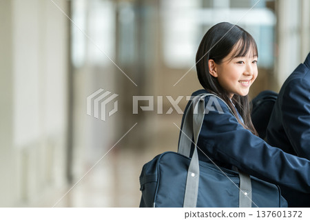 Junior high school girls in uniforms talking in the school corridor 137601372