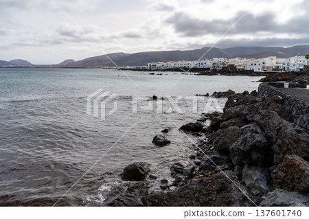 A serene view of Punta Mujeres in Lanzarote, showcasing the coastline with white buildings along the shore. 137601740