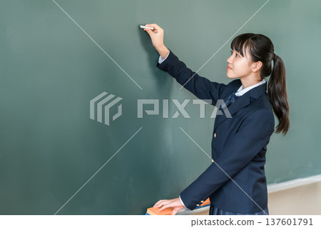一名國中女生在教室的黑板上用粉筆寫字 137601791