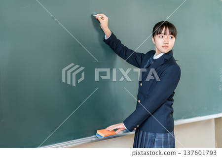 一名國中女生在教室的黑板上用粉筆寫字 137601793