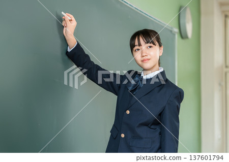 A female junior high school student writing with chalk on a blackboard in the classroom A female junior high school student writing with chalk on a blackboard in the classroom 137601794