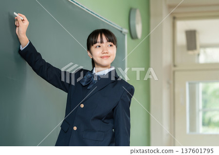 一名國中女生在教室的黑板上用粉筆寫字 137601795