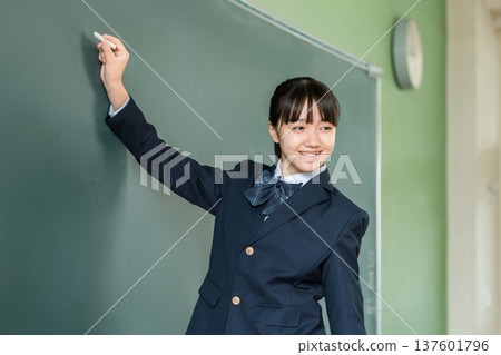 A female junior high school student writing with chalk on a blackboard in the classroom A female junior high school student writing with chalk on a blackboard in the classroom 137601796