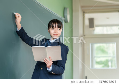 一名國中女生在教室的黑板上用粉筆寫字 137601801