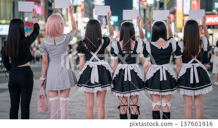 Female staff of a concept cafe (maid uniforms, rear view) soliciting customers in a busy area of Tokyo 137601916