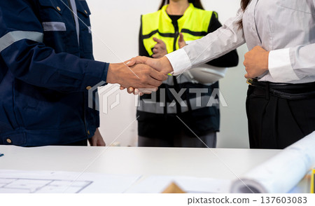 Construction workers, architects and engineers shake hands while working for teamwork and cooperation after completing an agreement in an office facility, successful cooperation concept. Construction workers, architects and engineers shake hands while working for teamwork and cooperation after completing an agreement in an office facility, successful cooperation concept. 137603083
