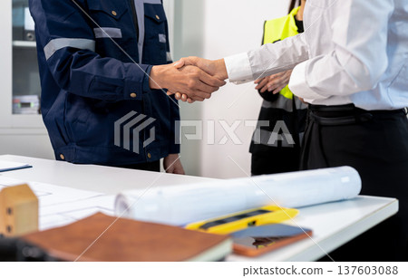 Construction workers, architects and engineers shake hands while working for teamwork and cooperation after completing an agreement in an office facility, successful cooperation concept. Construction workers, architects and engineers shake hands while working for teamwork and cooperation after completing an agreement in an office facility, successful cooperation concept. 137603088
