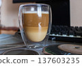 Layered Latte Macchiato in Double Walled Glass on Desk with Mechanical Keyboard 137603235