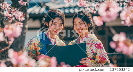 A female graduate in a kimono holding a diploma under cherry blossoms in full bloom A female graduate in a kimono holding a diploma under cherry blossoms in full bloom 137603242
