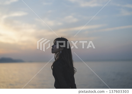 Woman looking at the sea at sunset Woman looking at the sea at sunset 137603303