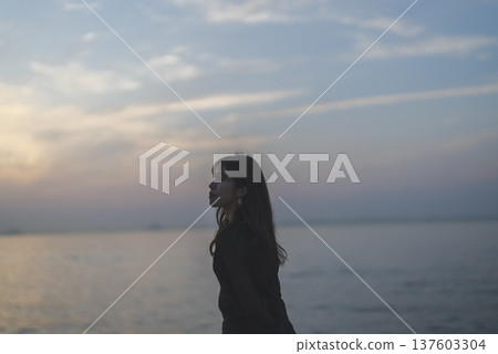 Woman looking at the sea at sunset Woman looking at the sea at sunset 137603304