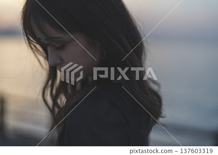 Woman looking at the sea at sunset Woman looking at the sea at sunset 137603319