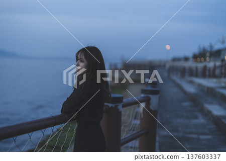 Woman looking at the sea at sunset 137603337