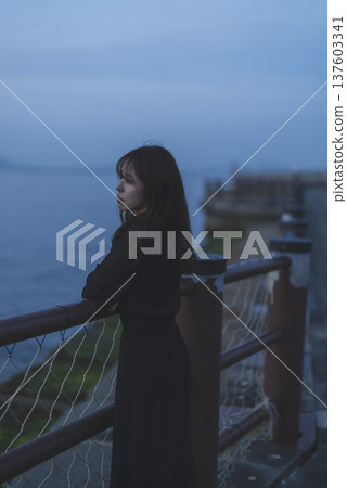 Woman looking at the sea at sunset Woman looking at the sea at sunset 137603341