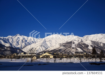 A view of Hakuba Station and the Ushiro-Tateyama mountain range bathed in the morning sun from near Tenjinzaka in Hakuba Village in the dead of winter A view of Hakuba Station and the Ushiro-Tateyama mountain range bathed in the morning sun from near Tenjinzaka in Hakuba Village in the dead of winter 137604531