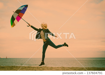Woman jumping with colorful umbrella on beach 137604791