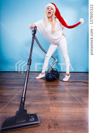 Funny girl in santa helper hat with vacuum cleaner Funny girl in santa helper hat with vacuum cleaner 137605322