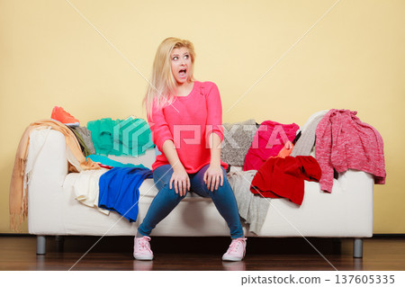 Woman does not know what to wear sitting on couch Woman does not know what to wear sitting on couch 137605335