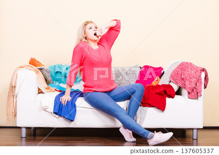 Woman does not know what to wear sitting on couch Woman does not know what to wear sitting on couch 137605337