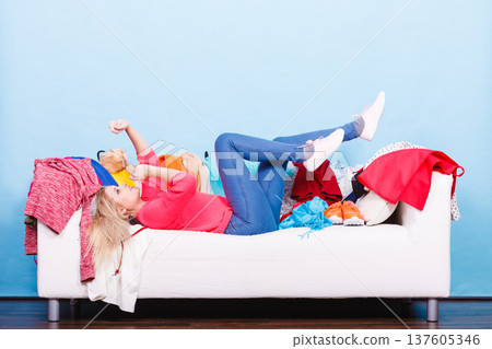 Woman does not know what to wear lying on couch Woman does not know what to wear lying on couch 137605346