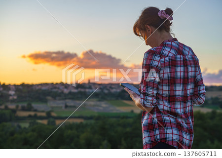 Woman taking picture from sunset over hilltop Puimoisson village, Provence France 137605711