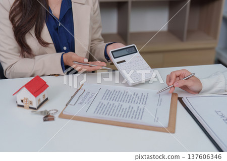 Real Estate Consultation. Agent using calculator to discuss property finances. Real Estate Consultation. Agent using calculator to discuss property finances. 137606346