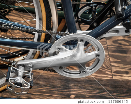 Close view of bicycle crankset and pedal showing metal and chain details in an indoor setting during daytime Close view of bicycle crankset and pedal showing metal and chain details in an indoor setting during daytime 137606545