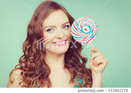 Smiling girl with lollipop candy on teal 137607274