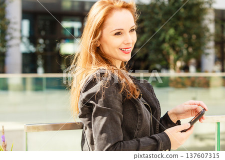 Girl using mobile phone on city street Girl using mobile phone on city street 137607315