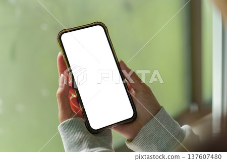 User displaying smartphone with blank screen in natural light User displaying smartphone with blank screen in natural light 137607480