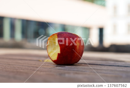 One red ripe bitten apple on a wooden table. Farm products. Dietary and vegan products One red ripe bitten apple on a wooden table. Farm products. Dietary and vegan products 137607562