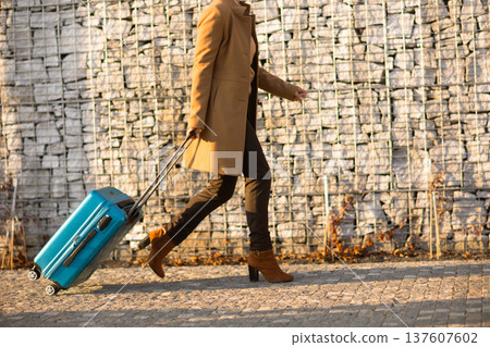 Solo Female Traveler with Blue Suitcase at Sunset 137607602