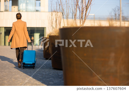 Woman Walking with Luggage Outside Modern Railway Station Woman Walking with Luggage Outside Modern Railway Station 137607604