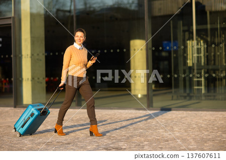 Smiling Woman with Luggage at Railway Terminal Plaza 137607611