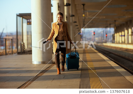 Smiling Woman Traveler with Suitcase at Train Station Smiling Woman Traveler with Suitcase at Train Station 137607618