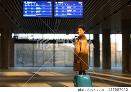 Smiling Woman Checking Train Times at Departure Board 137607630