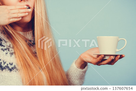Sleepy woman holding cup of coffee Sleepy woman holding cup of coffee 137607654