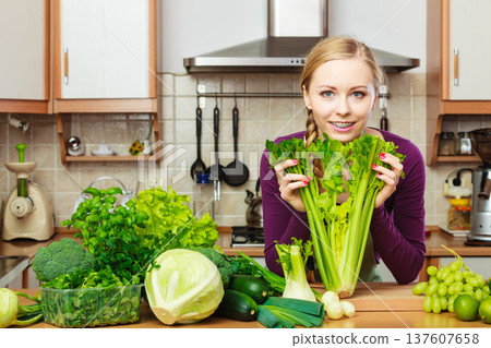 Woman in kitchen with green vegetables Woman in kitchen with green vegetables 137607658
